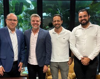 Quatro homens sorridentes em escritório com plantas ao fundo