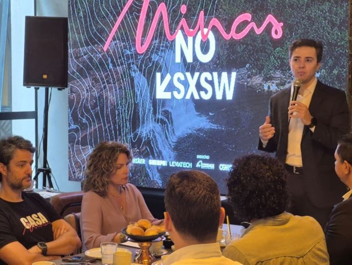 Diretor da Invest Minas apresenta projeto “Minas no SXSW” durante encontro em Belo Horizonte, com painel ao fundo e representantes do setor cultural e econômico reunidos.