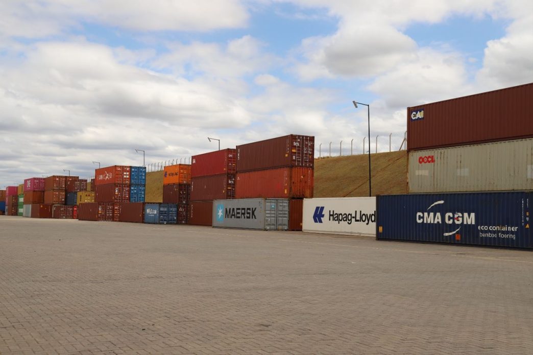 Pátio logístico com contêineres de exportação empilhados, simbolizando o crescimento do comércio exterior de Minas Gerais em 2026.