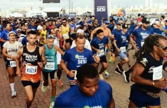 Grande grupo de corredores participa de prova da Corrida Nacional do SESI, largando em massa em evento esportivo de rua com atletas de diferentes idades.