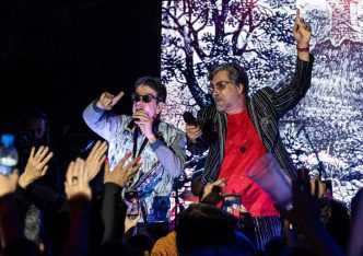 Fred Izak e George Israel se apresentam ao vivo no palco, interagindo com o público em show vibrante e cheio de energia.