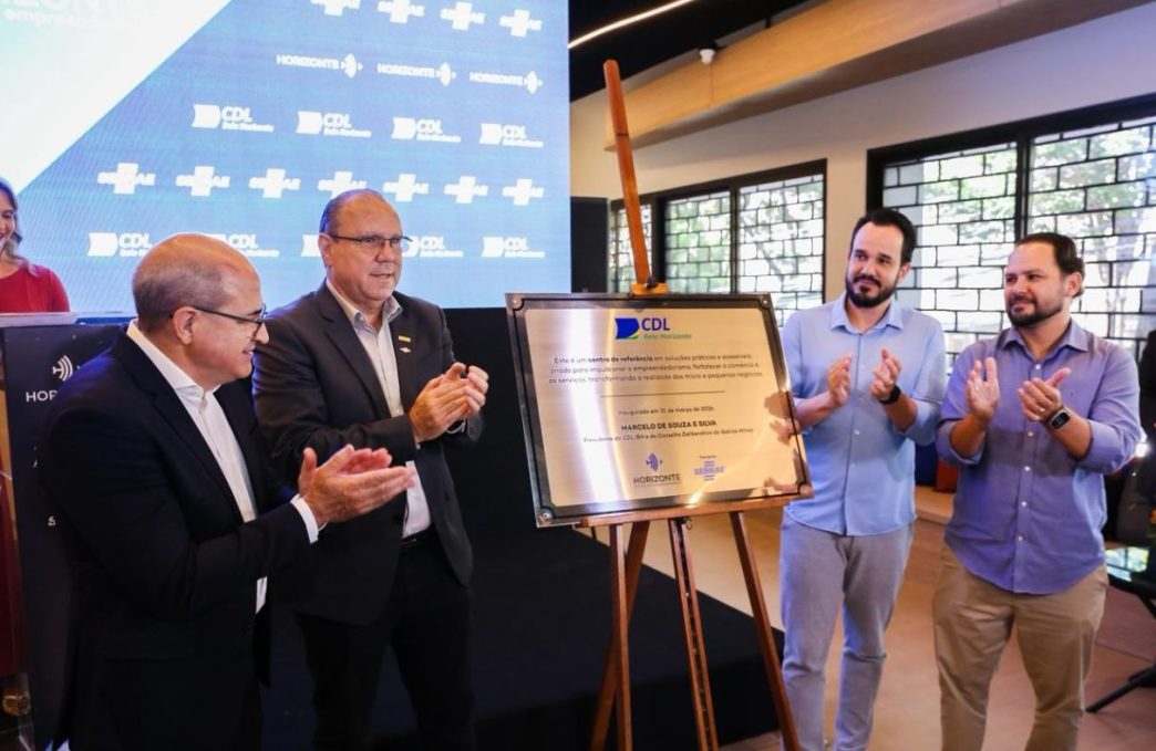 Autoridades e representantes do setor empresarial participam da inauguração do centro Horizonte, em Belo Horizonte, diante de placa comemorativa, enquanto aplaudem o lançamento do espaço.