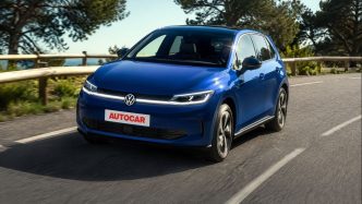 Volkswagen ID. Polo elétrico azul em movimento em estrada arborizada, com placa personalizada AUTOCAR e visual moderno da nova linha elétrica da marca.