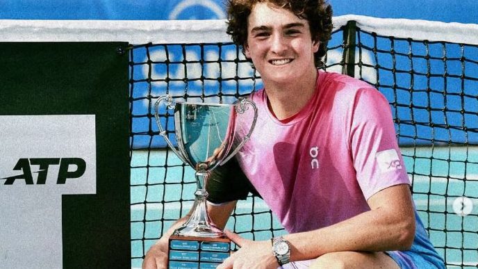 Jovem tenista com troféu ATP ao lado da rede