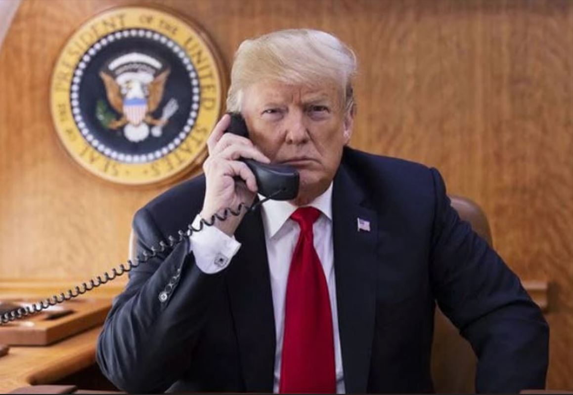 Donald Trump presidente dos estados unidos segura um aparelho de telefone no seu gabinete de trabalho.