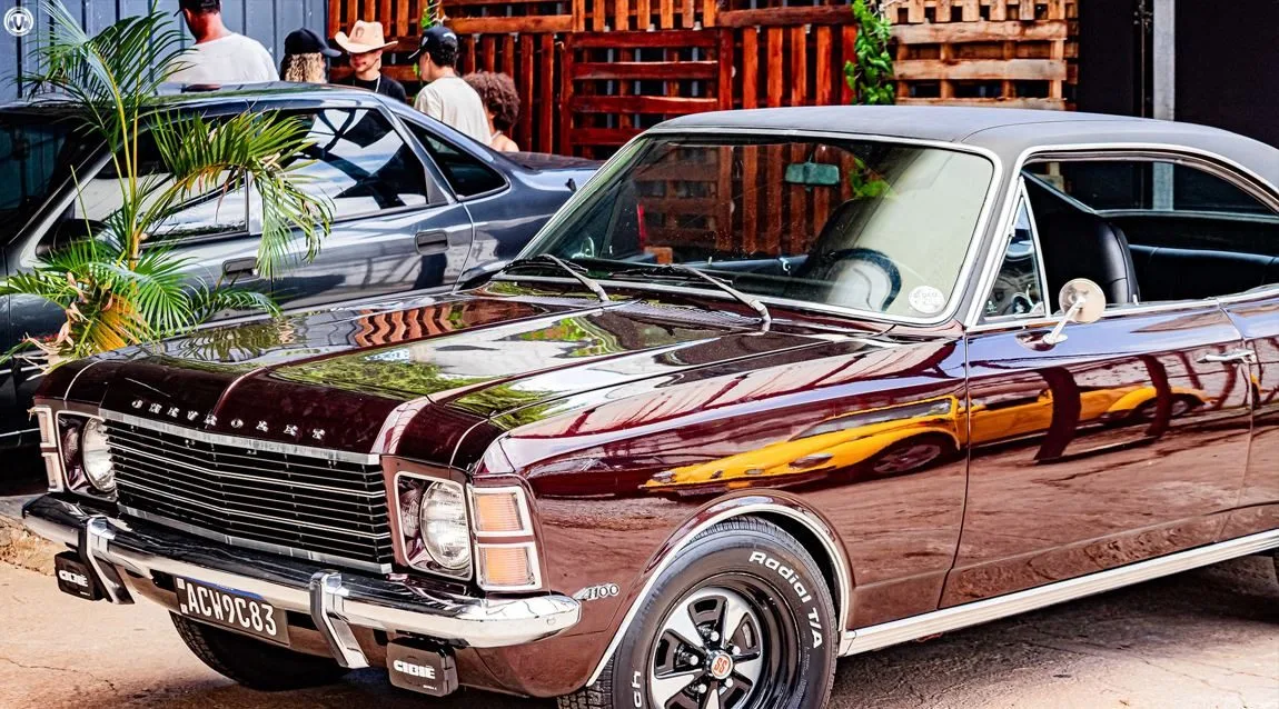 Chevrolet Opala cupê marrom metálico em destaque durante o maior encontro de carros antigos de Minas Gerais, com acabamento impecável, pneus esportivos e placa preta, atraindo olhares no Parque das Mangabeiras, em Belo Horizonte.
