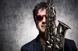 Foto do músico George Israel, ex-Kid Abelha, com saxofone em evidência, promovendo seu show “Baile do George” no Festival do Vinho, evento cultural gratuito com música ao vivo, gastronomia e vinhos internacionais em Belo Horizonte.