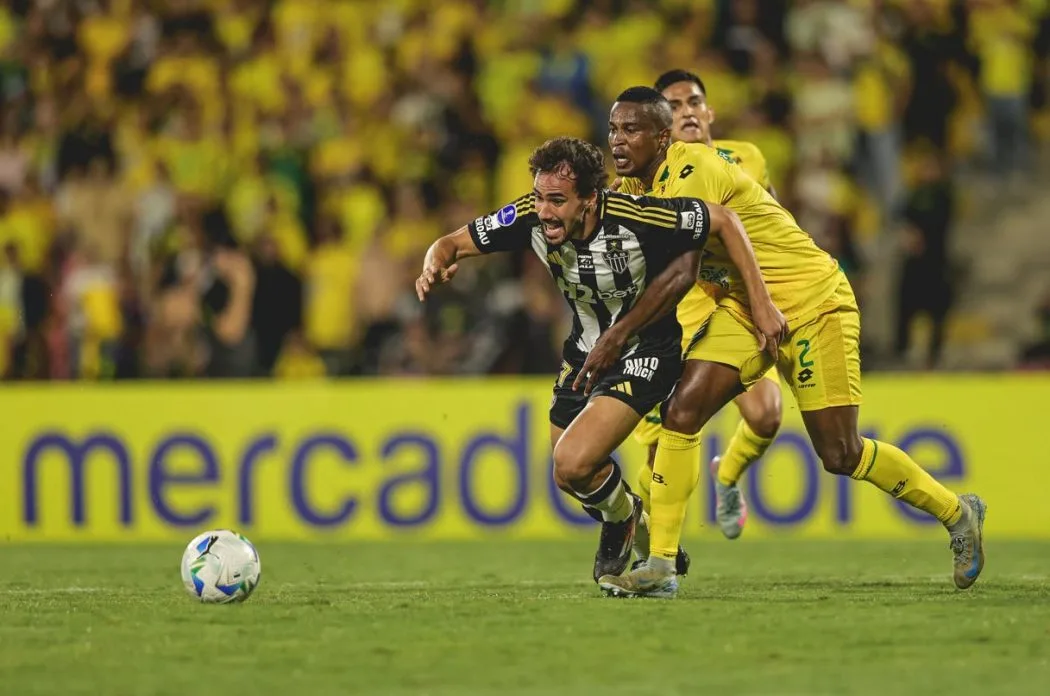 Igor Gomes, do Atlético Mineiro, é puxado por defensor do Bucaramanga durante jogada decisiva na partida válida pelos playoffs da Copa Sul-Americana 2025, na Colômbia.