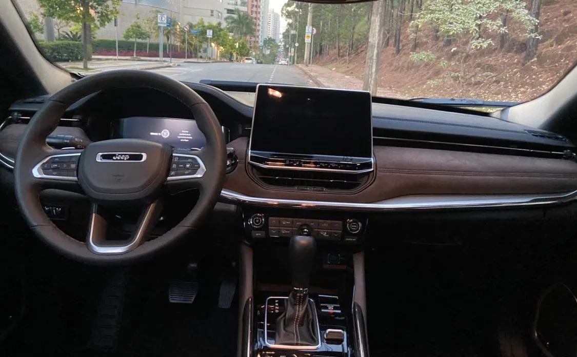 Painel frontal do Jeep Commander Overland 2025 com volante multifuncional, quadro de instrumentos digital, central multimídia flutuante de 10,1” e console central com seletor de câmbio automático, evidenciando o acabamento sofisticado e tecnológico do SUV.