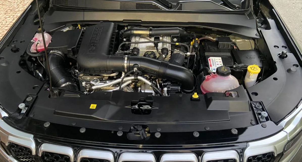 Novo motor 2.2 Turbodiesel do Jeep Commander 2025 em destaque sob o capô, com componentes visíveis do sistema de admissão, injeção eletrônica, intercooler e reservatórios, ressaltando a engenharia avançada voltada para desempenho e eficiência.