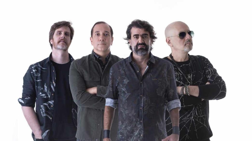 Integrantes da banda Biquíni posam em estúdio com expressão séria, vestindo roupas escuras, promovendo show no Festival Mineiro da Cerveja 2025.