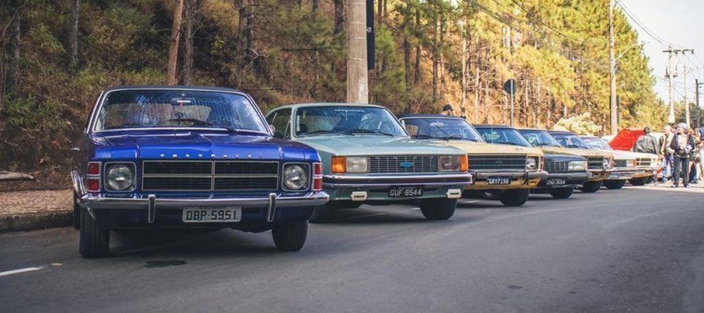 Cidade dos Carros chega à BH com clássicos, rock e gastronomia 2 Fila de Chevrolet Opala de diferentes cores estacionados em rua arborizada de Belo Horizonte durante encontro automotivo de clássicos.