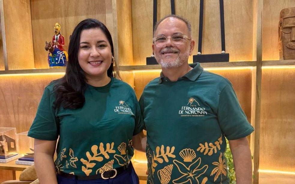 Débora Linhares e Hayrton Almeida durante o roadshow “Visite Fernando de Noronha”, vestindo camisetas oficiais do projeto, em ambiente decorado com peças de arte.