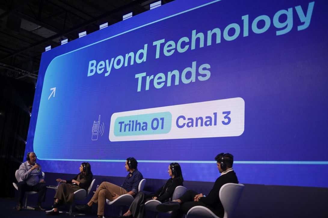 Painel com cinco especialistas sentados em cadeiras modernas, discutindo tendências tecnológicas no palco do Latam Retail Show, com uma grande tela de LED ao fundo exibindo o tema “Beyond Technology Trends – Trilha 01, Canal 3”.