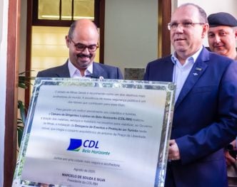 O vice governador de Minas Gerais e o presidente da CDL BH, Marcelo de Souza e Silva seguram placa comemorativa em um evento em BH.