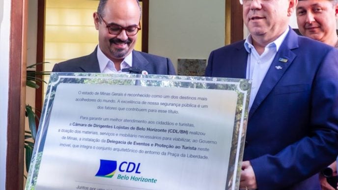 O vice governador de Minas Gerais e o presidente da CDL BH, Marcelo de Souza e Silva seguram placa comemorativa em um evento em BH.