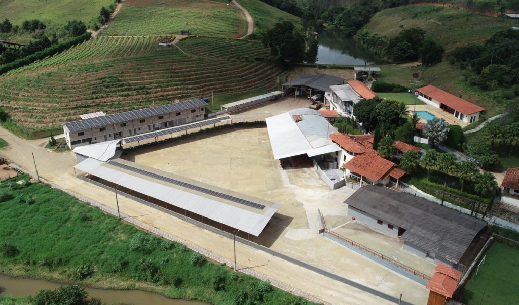 Vista aérea do Parque Cervejeiro da Cervejaria Loba, em Santana dos Montes, com estruturas modernas cercadas por áreas verdes e lago.