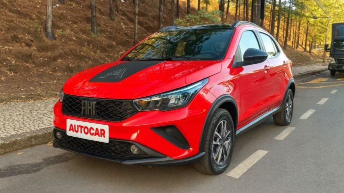 Fiat Argo Trekking 2026 vermelho estacionado em rua arborizada, com destaque para o design frontal renovado, faróis Full-LED e detalhes em preto brilhante.