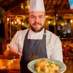 Chef do restaurante Ô Chefe São Bento apresenta prato de massa artesanal em ambiente iluminado e aconchegante do salão.