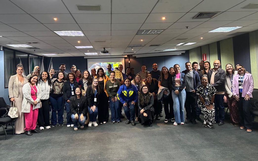 Grupo diverso de profissionais e educadores do Senac em Minas, reunidos em ambiente corporativo, durante evento do Programa Acolha que promove inclusão, saúde emocional e bem-estar estudantil.