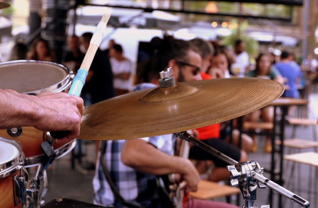 Detalhe de apresentação musical ao vivo no Porks Castelo, com foco em baterista em ação e público ao fundo durante o evento.