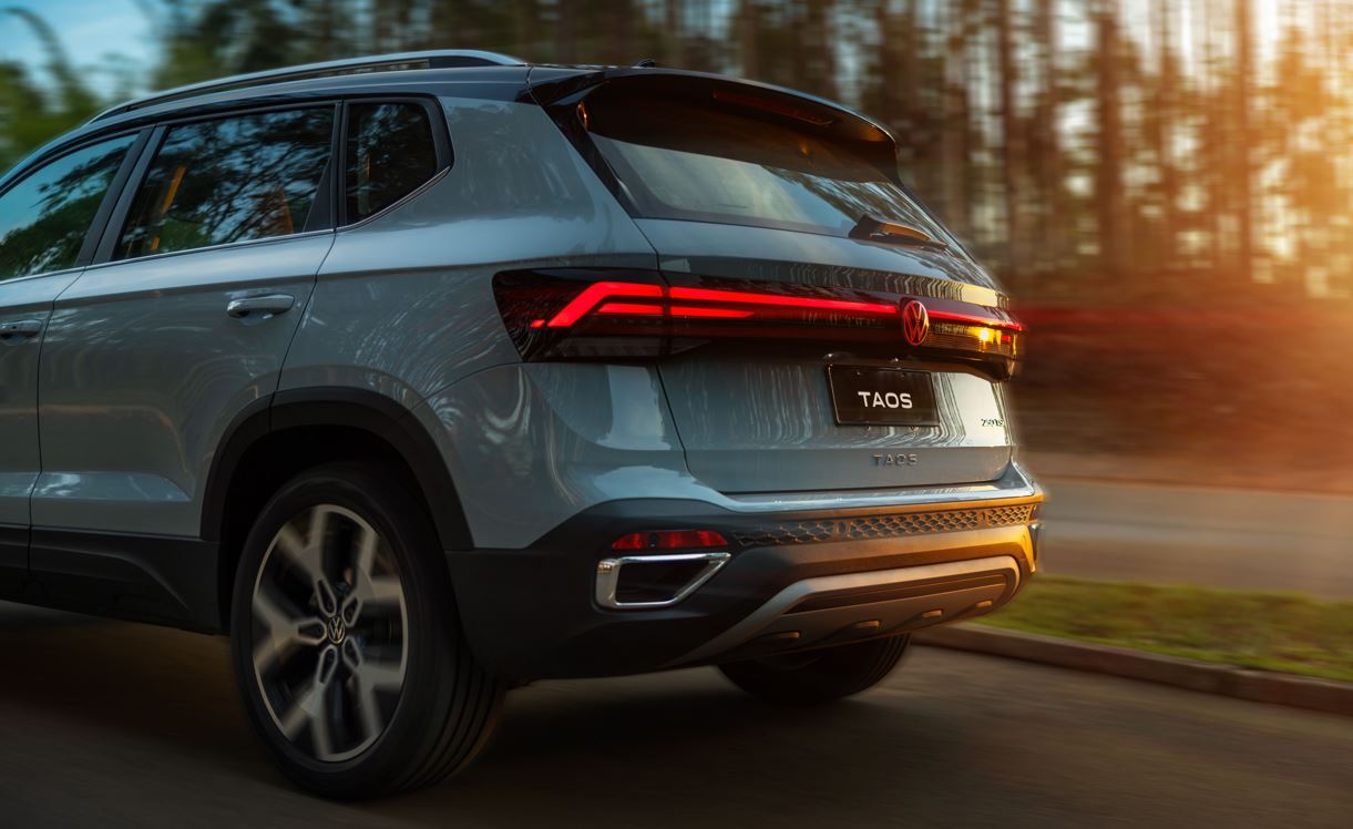 Traseira do Volkswagen Taos 2026 com lanternas em LED e logotipo iluminado em vermelho, em estrada ao entardecer.