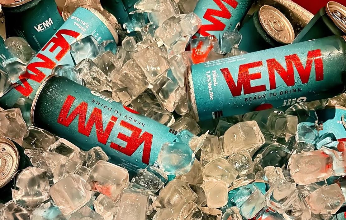 Latas da bebida VENM mergulhadas em gelo, destacando o rótulo azul vibrante e o design moderno da embalagem.