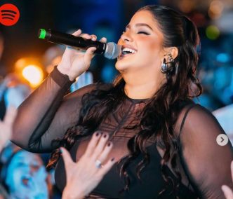 Cantora se apresenta em palco com microfone, cantando com expressão vibrante durante show ao vivo em Belo Horizonte