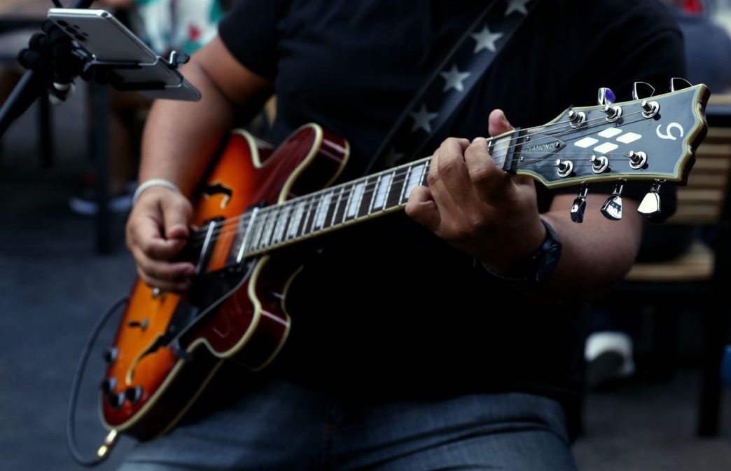 Músico toca guitarra elétrica durante apresentação de rock ao vivo em ambiente descontraído, ilustrando a proposta musical do Carna Porks 0800 em Belo Horizonte.