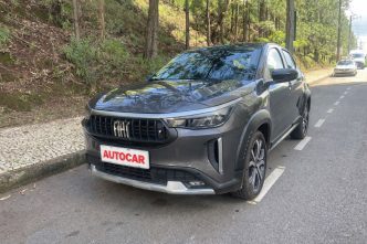 Fiat Pulse Impetus Hybrid 2026 cinza estacionado em via urbana arborizada, com nova grade frontal, faróis em LED e placa personalizada AUTOCAR.