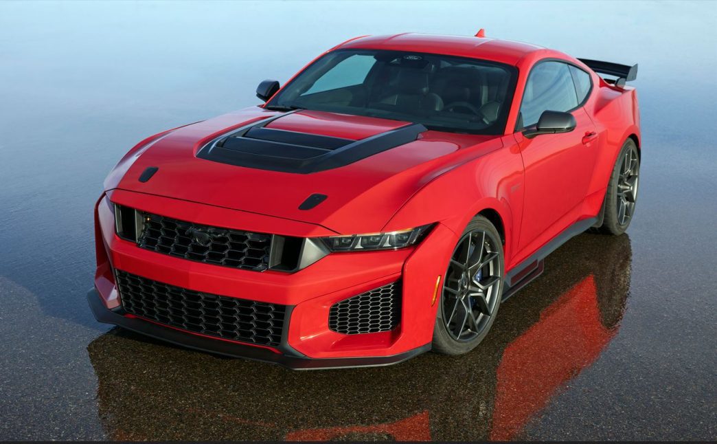Novo Mustang Dark Horse SC 2026 vermelho parado em superfície molhada, destacando frente agressiva, capô aerodinâmico e rodas esportivas.
