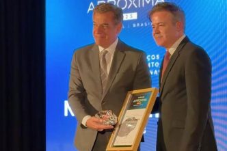 Nadim Elias Donato Filho recebe o Prêmio Aproxima Portugal–Brasil durante cerimônia no Porto, segurando troféu e certificado ao lado de representante da organização.