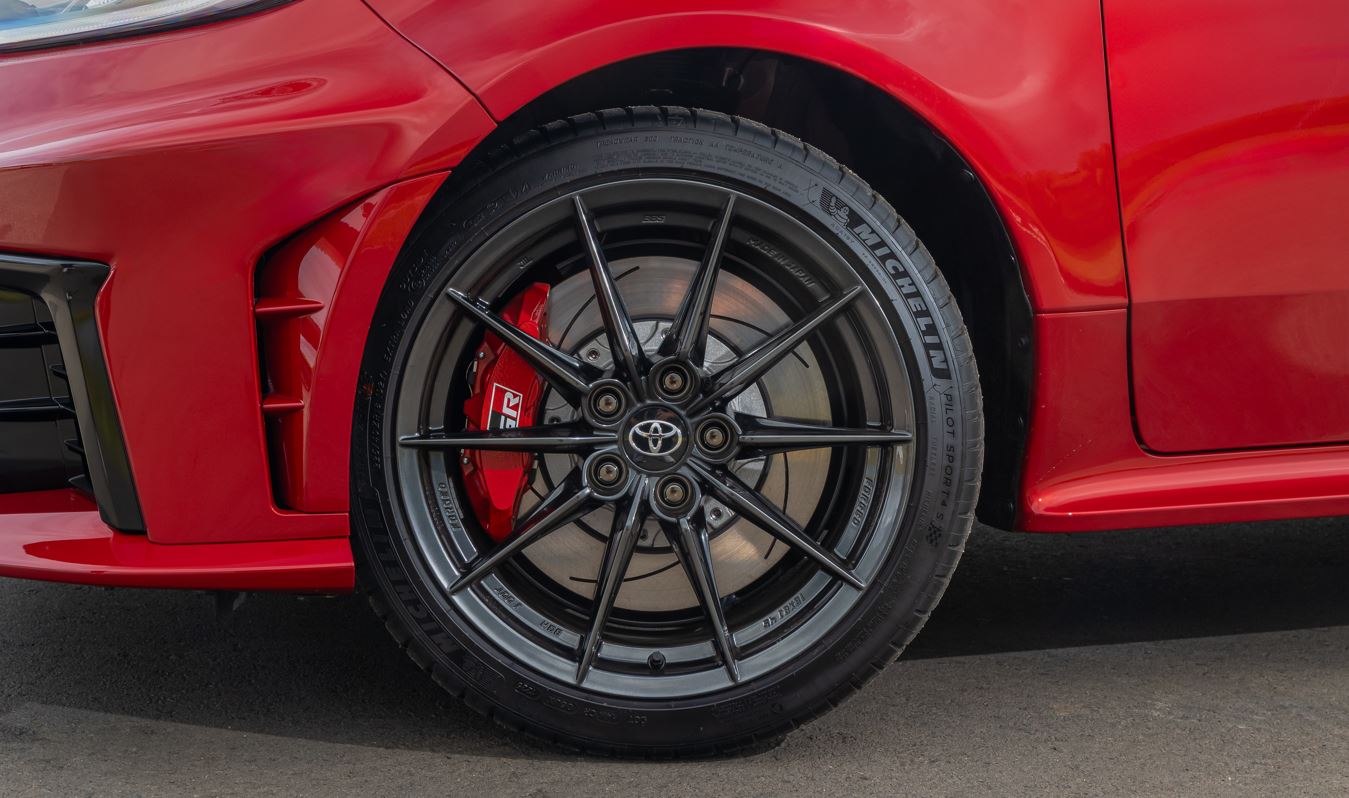 Roda de liga leve forjada de 18 polegadas do Toyota GR Yaris, com acabamento preto, pinça de freio vermelha GR e pneus Michelin de alta performance.