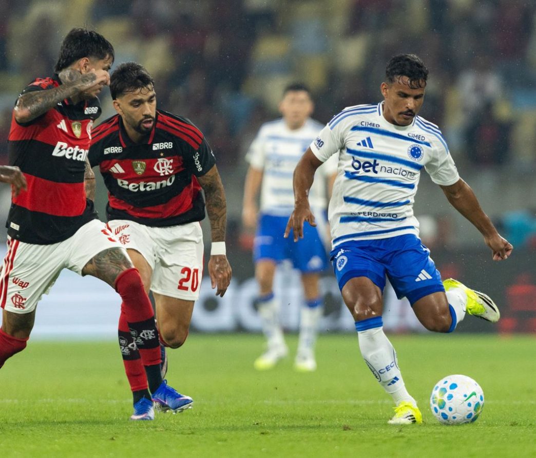 Jogador do Cruzeiro disputa a bola com dois atletas do Flamengo durante partida da Série A do Campeonato Brasileiro no estádio do Maracanã, no Rio de Janeiro.
