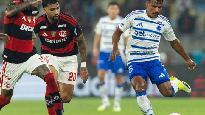 Jogador do Cruzeiro disputa a bola com dois atletas do Flamengo durante partida da Série A do Campeonato Brasileiro no estádio do Maracanã, no Rio de Janeiro.