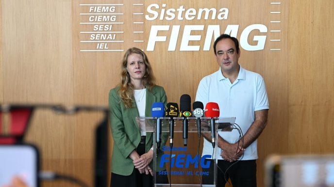 Dirigentes da FIEMG e da Codemge em coletiva à imprensa, diante de púlpito com microfones, durante anúncio da aquisição do Expominas Juiz de Fora, em Belo Horizonte.