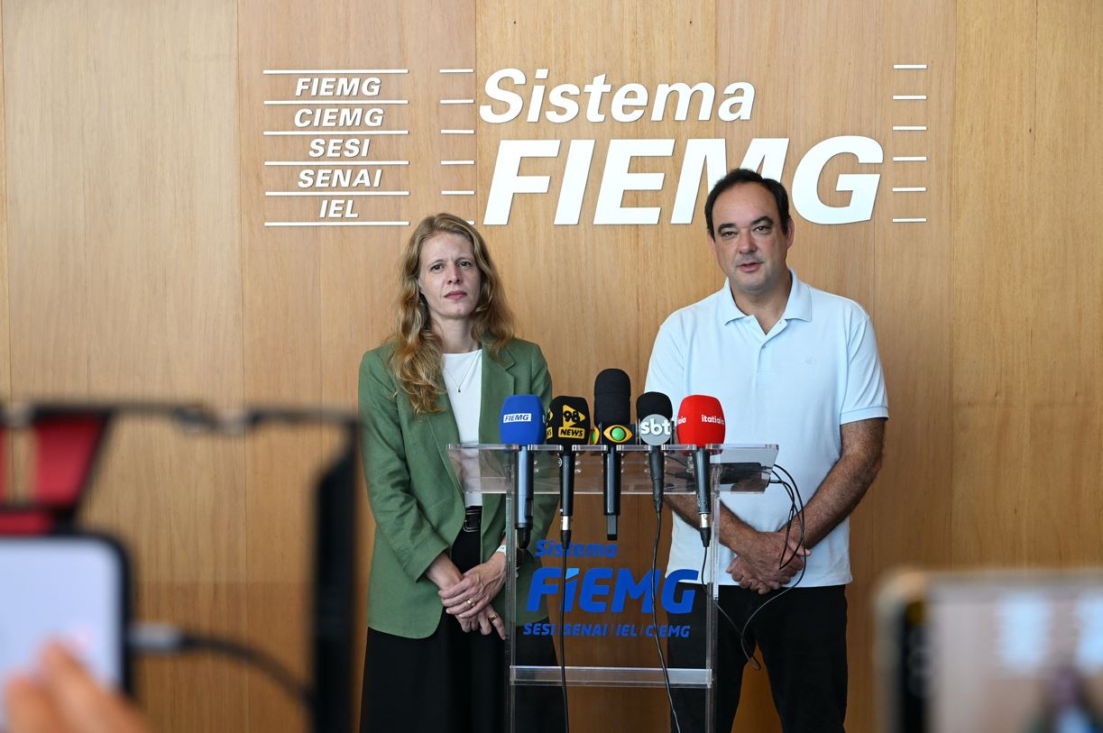 Dirigentes da FIEMG e da Codemge em coletiva à imprensa, diante de púlpito com microfones, durante anúncio da aquisição do Expominas Juiz de Fora, em Belo Horizonte.