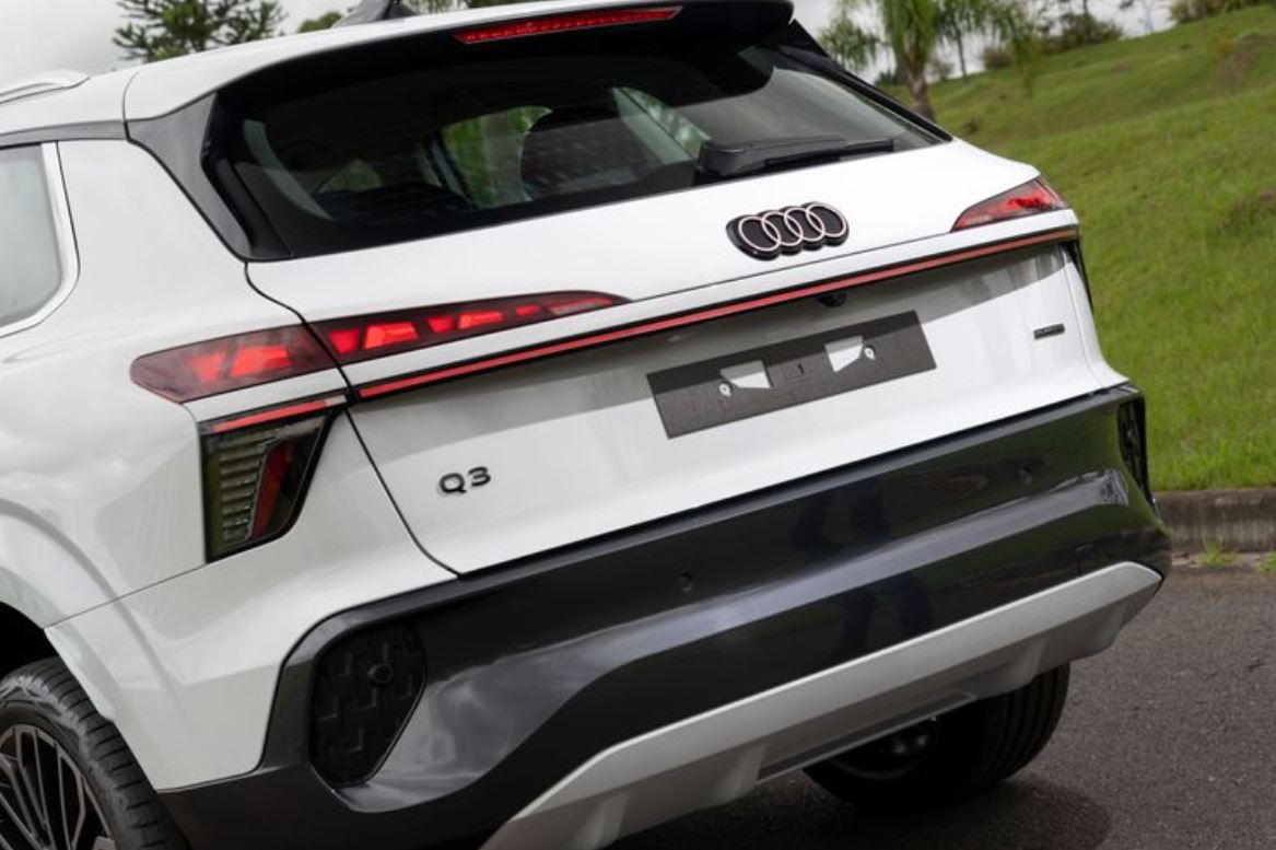 Traseira do novo Audi Q3 branco com lanternas em LED interligadas por faixa luminosa e logotipo das quatro argolas no centro.