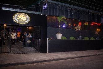 Fachada do 299 Speed Shop à noite em Belo Horizonte, com iluminação em neon, entrada movimentada e pessoas reunidas na porta.