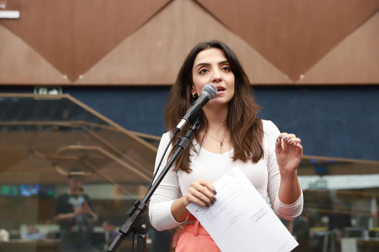 Vereadora de Belo Horizonte discursa em plenário, segurando documento e falando ao microfone durante sessão legislativa