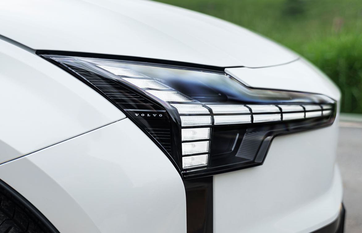 Detalhe do farol dianteiro em LED do Volvo EX30 Ultra Twin Motor, destacando o design moderno e a assinatura luminosa do SUV elétrico.