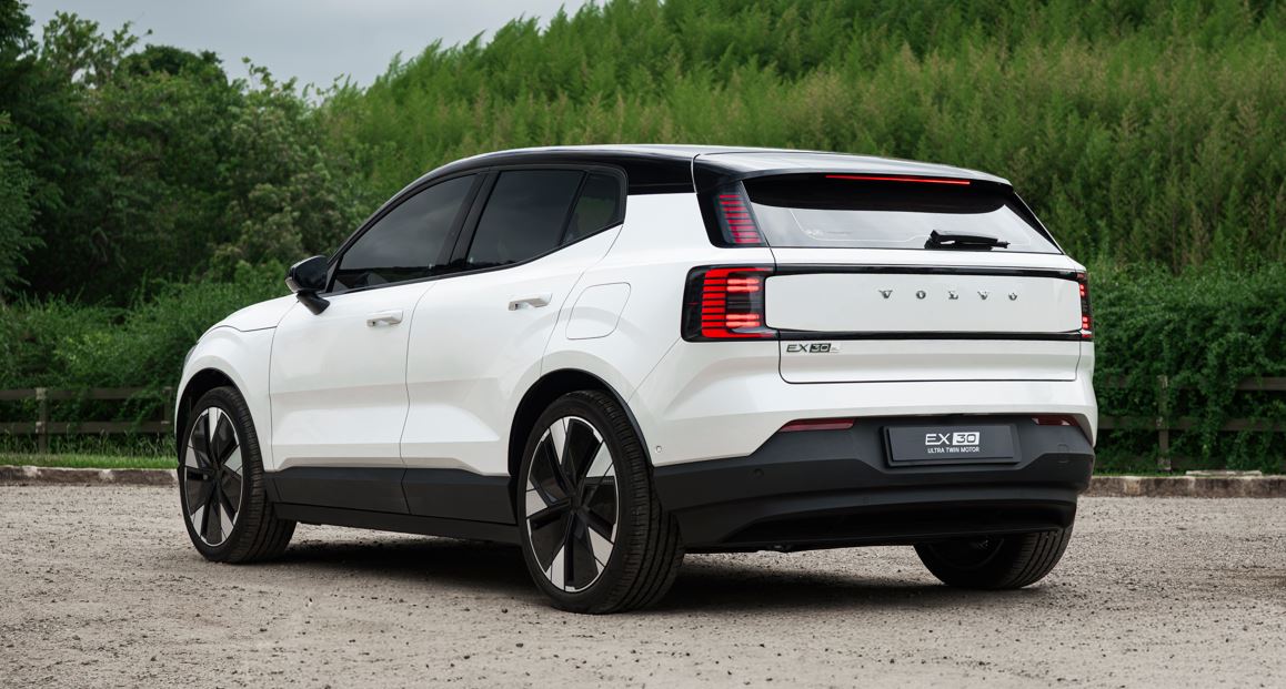 Volvo EX30 Ultra Twin Motor visto pela traseira em estrada rural, destacando lanternas em LED, rodas de 20 polegadas e design do SUV elétrico.