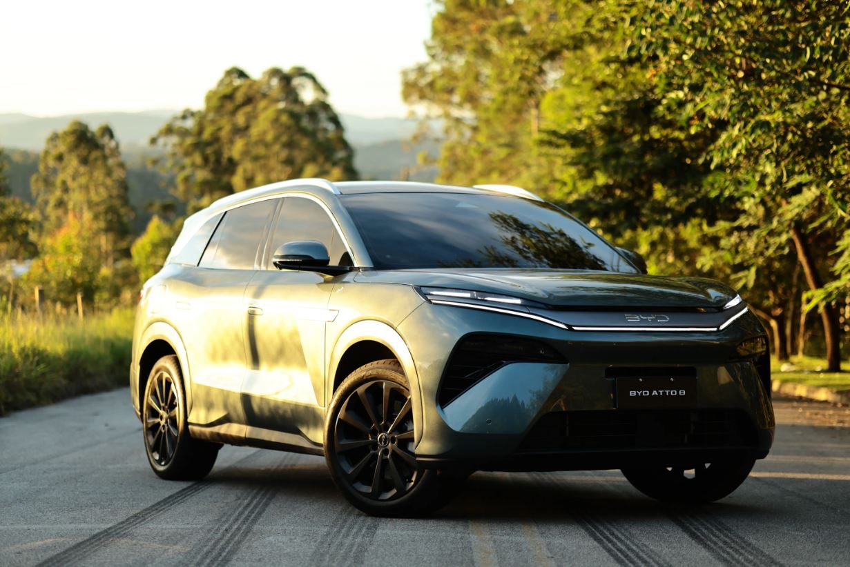 BYD Atto 8 SUV híbrido plug-in em estrada arborizada, com design moderno, linhas robustas, iluminação em LED e acabamento sofisticado