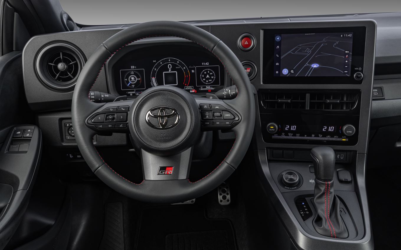 Painel do Toyota GR Yaris com volante esportivo, cluster digital de 12,3 polegadas e central multimídia integrada.