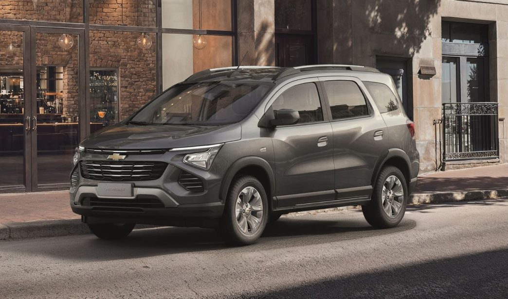 Chevrolet Spin 2027 na cor cinza estacionada em área urbana, destacando o novo design frontal, grade escurecida e rodas redesenhadas.
