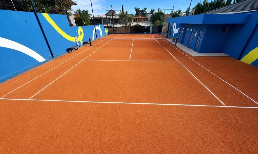 Quadra de tênis da nova unidade Fast Tennis no bairro Belvedere, em Belo Horizonte, com piso de saibro sintético, estrutura moderna e área preparada para aulas e treinos.