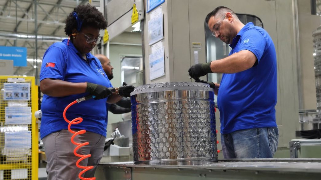 Funcionários trabalham em linha de produção industrial em Minas Gerais, refletindo crescimento econômico e geração de empregos no estado.