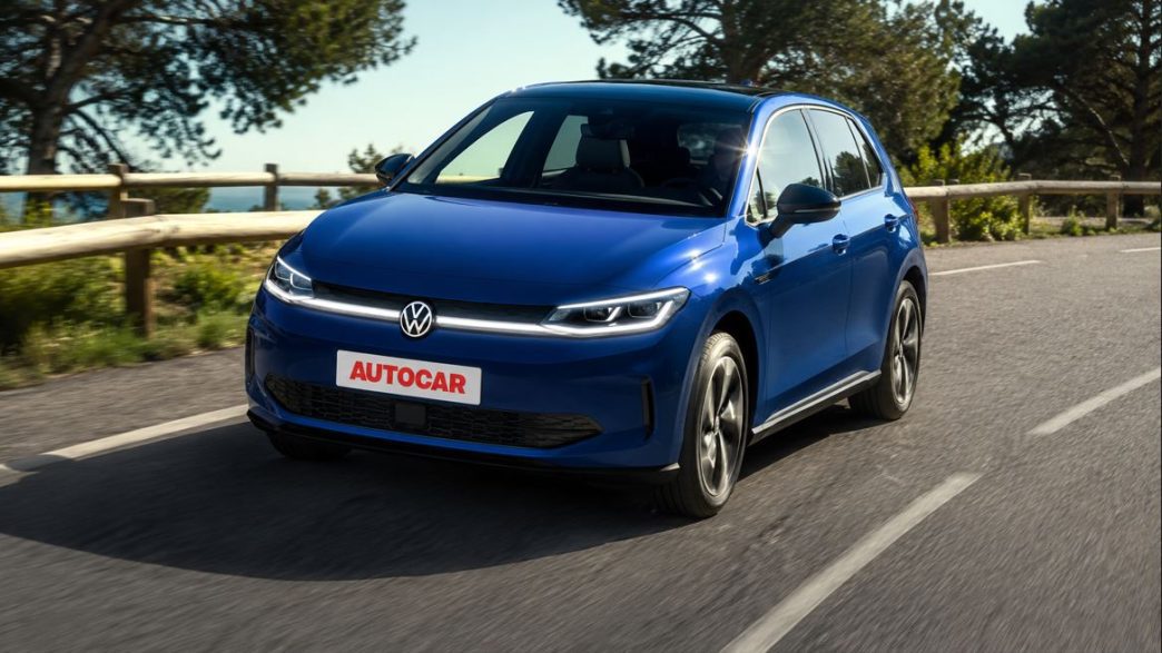 Volkswagen ID. Polo elétrico azul em movimento em estrada arborizada, com placa personalizada AUTOCAR e visual moderno da nova linha elétrica da marca.