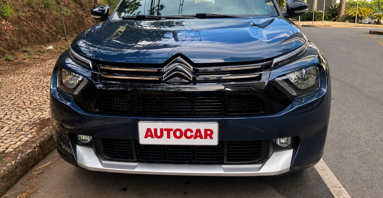 Detalhe frontal do Citroën Aircross XTR 7 2026 azul, com grade preta, faróis divididos, emblema Citroën cromado e placa AUTOCAR usada na avaliação.