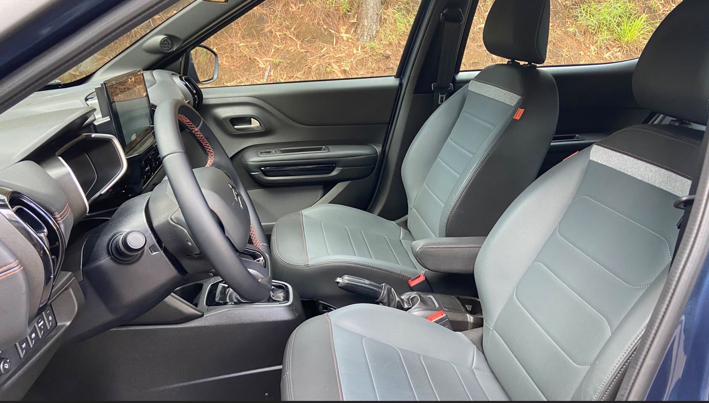 Interior do Citroën Aircross XTR 7 2026 com bancos dianteiros em revestimento cinza, volante multifuncional, central multimídia e acabamento com costuras aparentes.